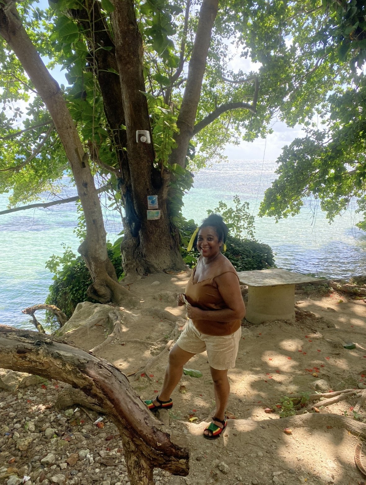 Julette Joy Prayogg smiling beneath a large tree by the sea